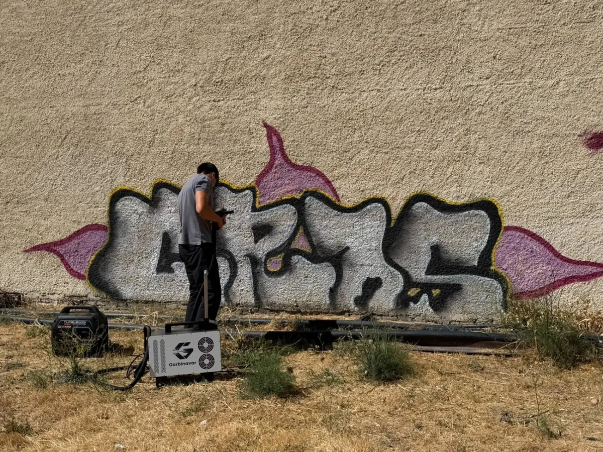 Operario de Garbinavar con el equipo láser eliminando un grafiti de un muro